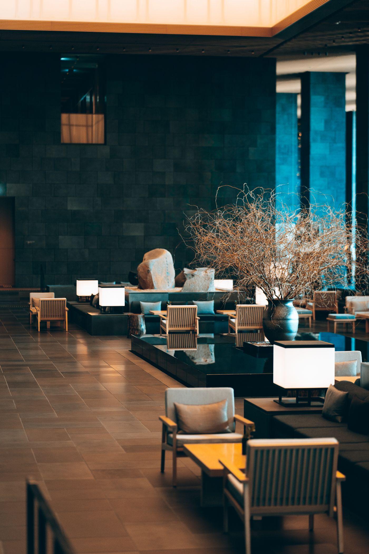 Hotel lounge with low seating, lamps and a stone feature wall
